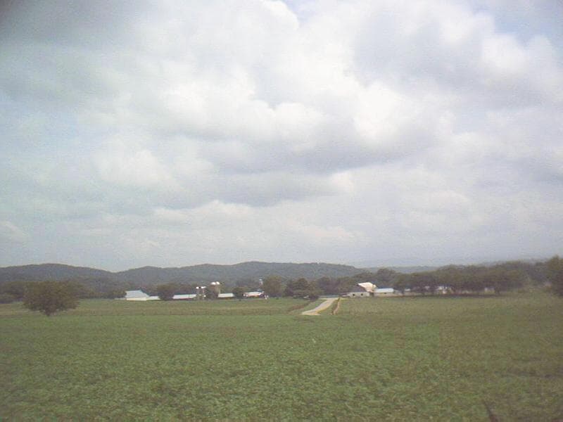 Rolling farmland in East Tennessee with a wooden fence in the foreground