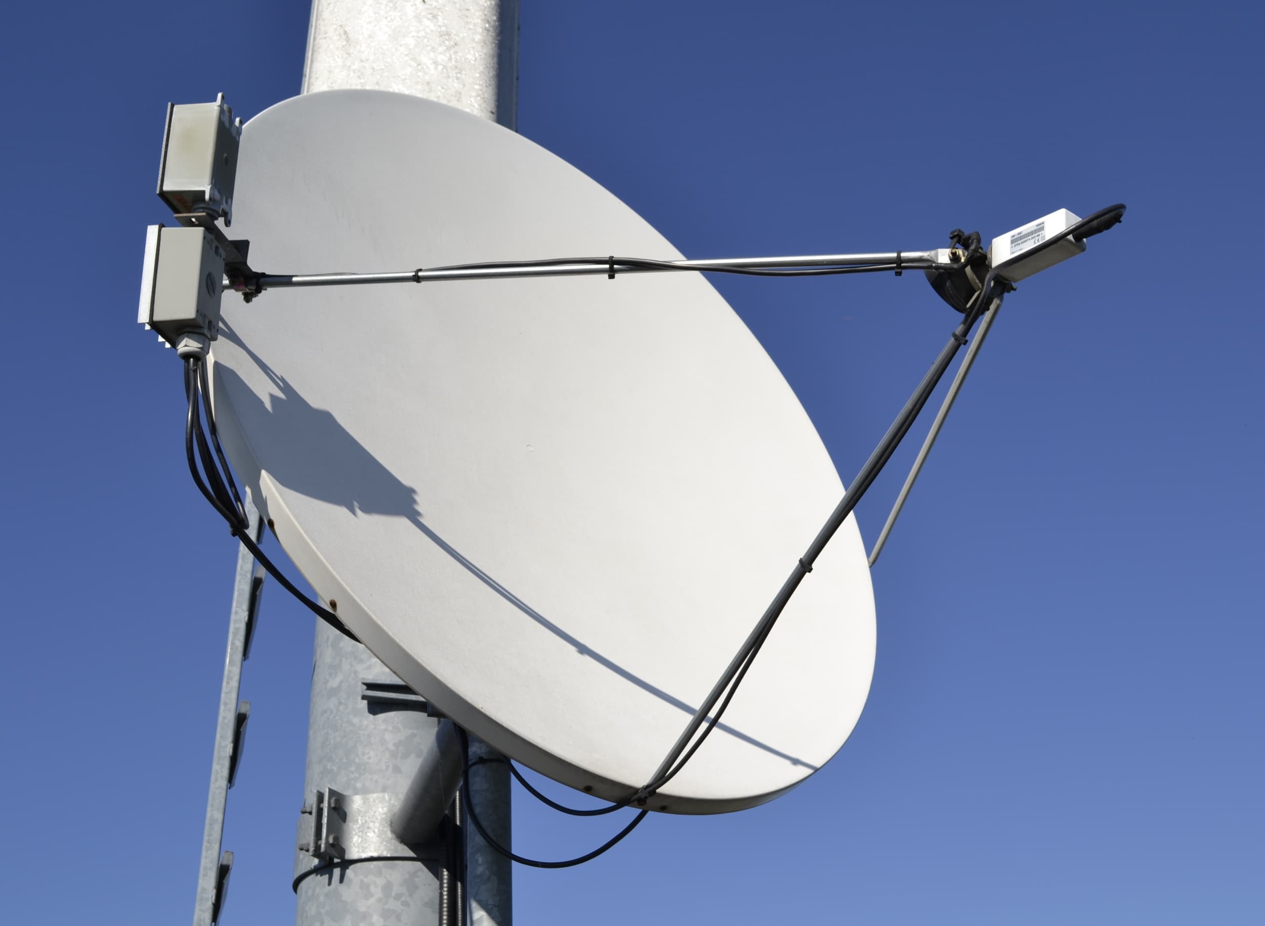 A satellite dish mounted on a rural property with open countryside in the background